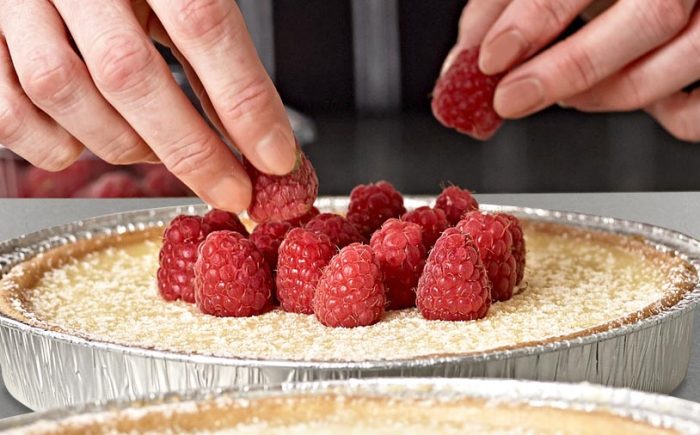 Adding raspberry toppings to a cheesecake