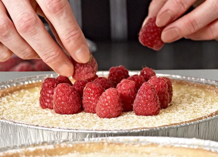 Adding raspberry toppings to a cheesecake